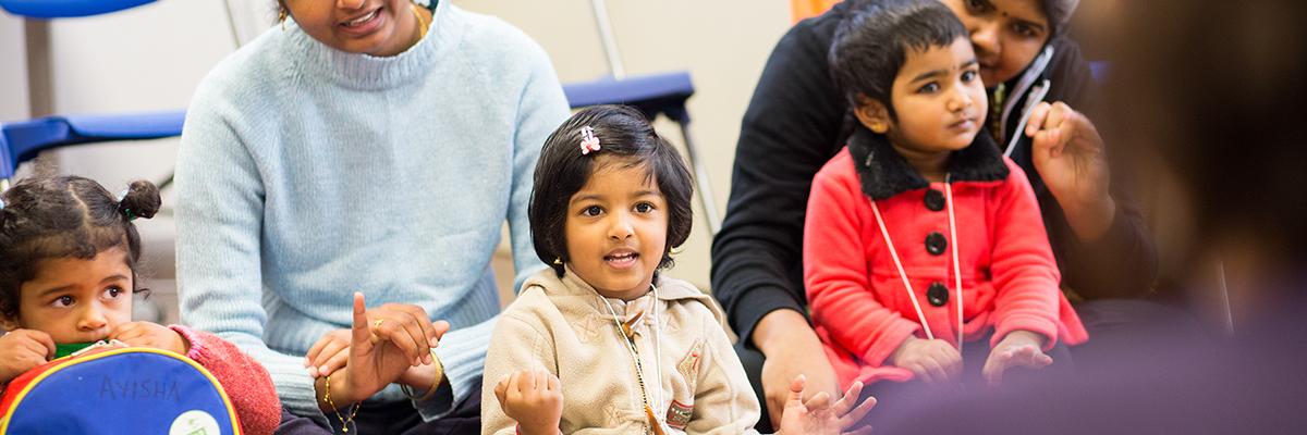 Young children and mothers watching a library presentation