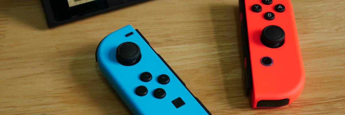 Red & blue Nintendo switch controllers on a table in front of a tablet screen