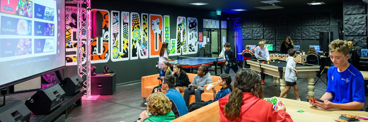 Young people playing various games and activities inside a youth centre