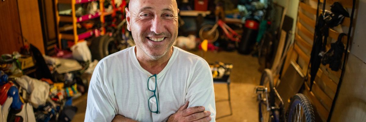 Smiling middle aged man standing in room filled with items