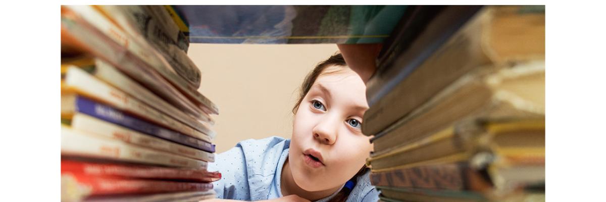 Child looking through a stack of books