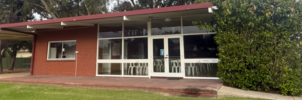 Front of Memorial Park Hall showing white-framed windows overlooking a verandah and grassed area.