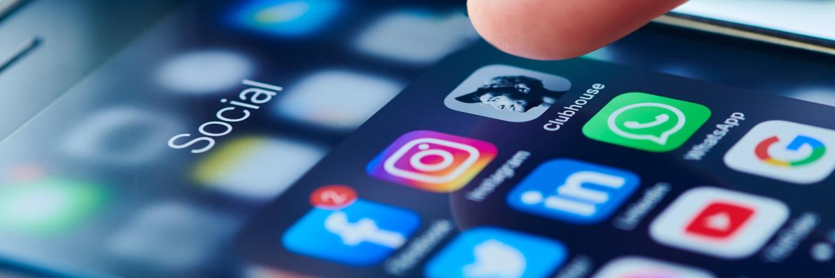 A finger hovering over a smartphone screen full of social media apps