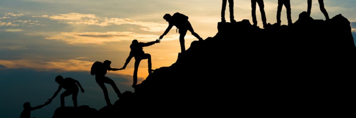 Group of men on peak mountain climbing helping team work 