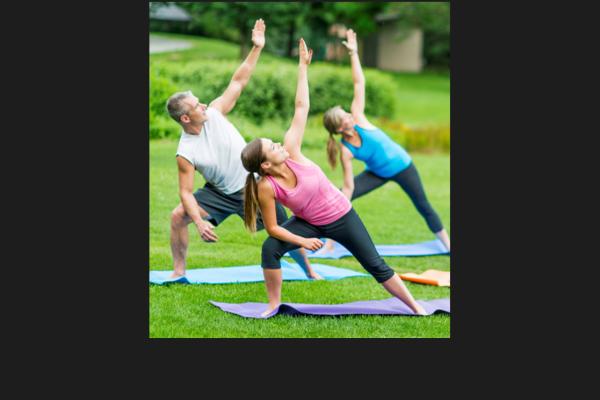 Three people doing yoga in a park
