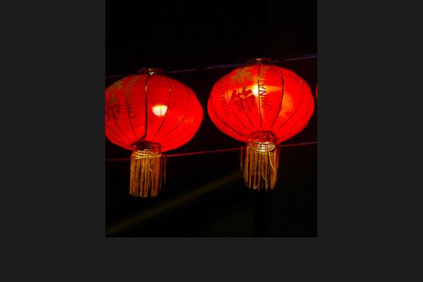 Two chinese lanterns glowing red against the night sky