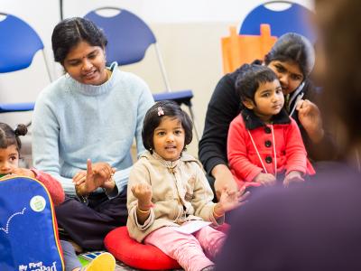 Young children and mothers watching a library presentation