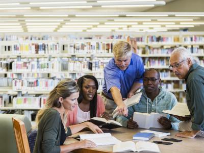 Five adults discussing books in a library