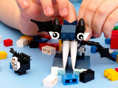 Child's hands building a figurine out of LEGO bricks.