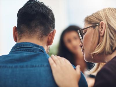 Woman comforting man with her hand on his shoulder