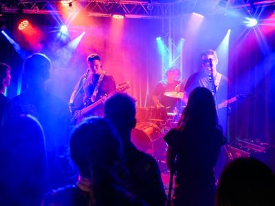 Band Performing on a stage with Blue and Red Lights shining through haze