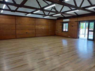 Wooden rafters with fluorescent lights, mud brick walls, wood-look vinyl flooring overlooking back double doors and window to back courtyard.