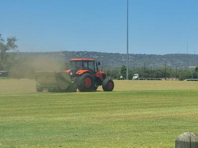 Large tractor towing verti-mower on sports ground at Mills Park