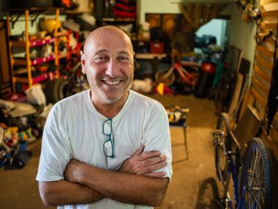 Smiling middle aged man standing in room filled with items