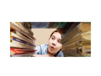 Child looking through a stack of books