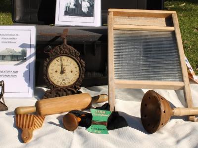 History box with contents including sad iron, wash board, dolly stick, butter pats, scales and Robin Starch box.