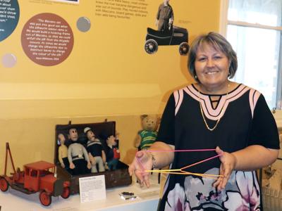 Mayor Terresa Lynes reacquaints herself with finger strings at the When We Were Young exhibition, opening this weekend at the City of Gosnells Museum.