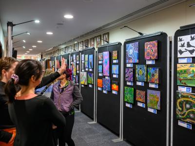 Exhibition with Aboriginal artwork and on the left people are observing it