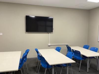Desks with chairs and a TV mounted to the wall