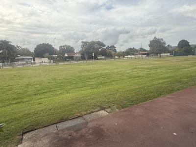 Grassed area in front of hall with wooden post and rail fencing