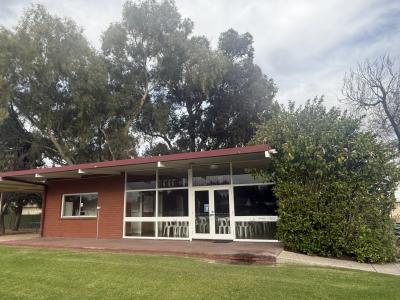 Front of Memorial Park Hall showing white-framed windows overlooking a verandah and grassed area.
