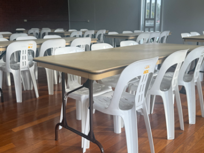 Timber floor with rectangular tables and white plastic chairs
