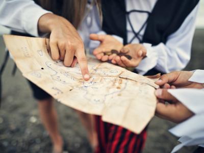 Children dressed as pirates, holding and pointing at a treasure map