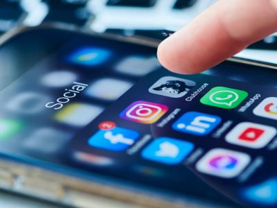 A finger hovering over a smartphone screen full of social media apps
