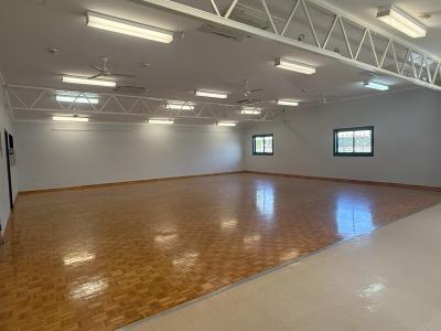Inside Southern River Hall with carpeted area in foreground, timber parquetry flooring in main hall section and fluorescent lighting