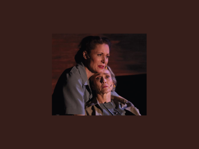 A woman on stage with a severe, desperate facial expression holds another, older woman, as she appears to be dying.