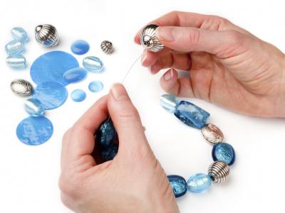 Hands making a beaded charm