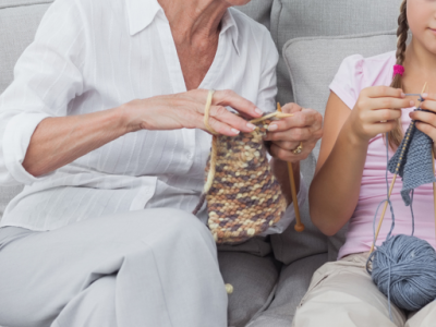 Older lady and young girl knitting on couch together