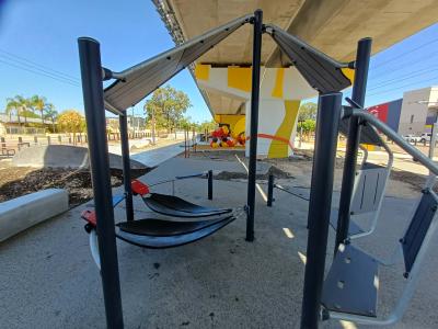 Skate park under shade of overhead rail line with casual seating