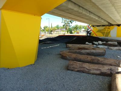 Wooden logs under shade of overhead rail line