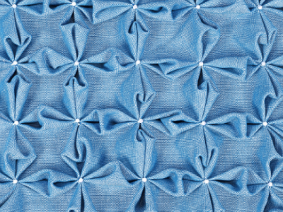 A pale blue cotton-like fabric, smocked into four-petal floral patterns
