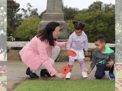 City of Gosnells Councillor and ex-servicewoman Kylie Dalton plants paper poppies with Shilo and Tobias at Anzac Gardens in Gosnells.