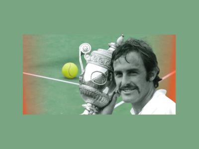 John Newcombe holds a trophy. Tennis court in background.