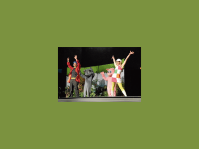 Goldilocks, 2 bears and a man stand on stage, with their arms raised in the air looking joyful.