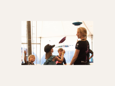 Children spinning plates, with a circus instructor supervising them